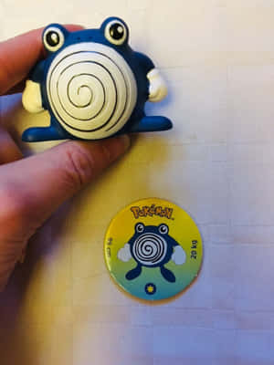 手拿著 Psyduck 公仔在官方 Pokémon 徽章上方。 — 寶可夢 壁紙