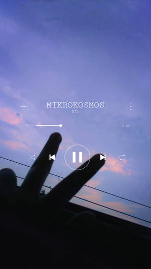 在暮色天空下做出和平手勢的手，帶有音樂播放器疊加層。 — 美學音樂 壁紙