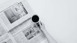 手拿咖啡杯在單色報紙標題上方。 — Old Paper 壁紙