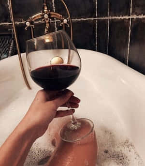 手在泡泡浴中拿著酒杯，旁邊有復古黃銅水龍頭。 — 葡萄酒 壁紙