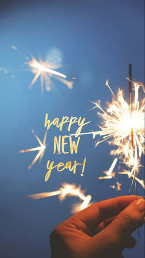 手拿煙火與「happy new year」文字在藍色天空背景下 — 慶祝 壁紙