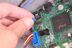 手將藍色電纜連接到帶有Intel晶片的綠色電路板。 — 主機板 壁紙