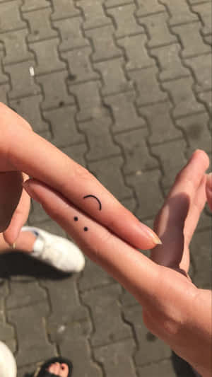 一隻手在戶外，指尖上繪有一個細小笑臉。 — 笑臉 壁紙