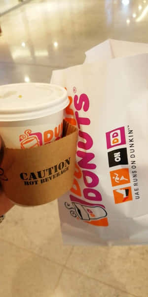 手在瓷磚地板上拿著Dunkin' Donuts咖啡杯和袋子。 — Dunkin Donuts 壁紙