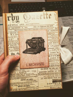 手拿著19世紀的報紙，帶有打字機插圖和復古廣告。 — Old Paper 壁紙