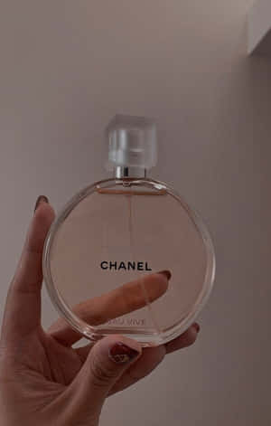 手拿著 Chanel Eau Vive 香水瓶，指甲塗有粉紅色指甲油。 — Galaxy Tab Active5 壁紙