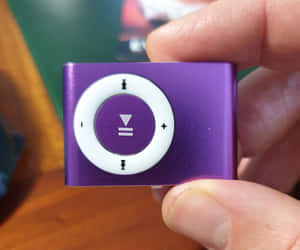 手拿著紫色 iPod shuffle 音樂播放器。 — 音樂 壁紙