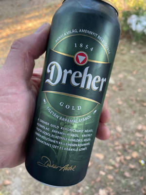 戶外手持綠色和金色的Dreher Gold啤酒罐。 — 啤酒 壁紙