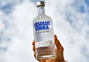 手拿Absolut Vodka酒瓶，背景陰天 — 天空 壁紙