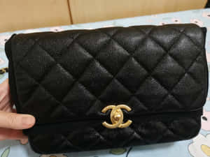 黑色絎縫Chanel手袋，帶金色CC標誌，握在手中。 — 香奈兒標誌 壁紙