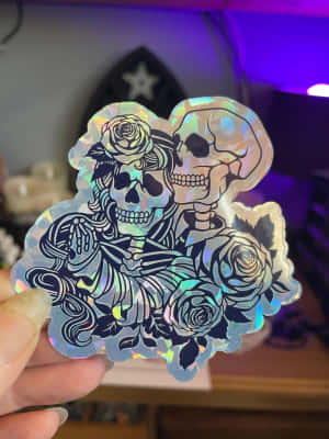 手在紫色光下拿著骷髏頭和玫瑰全息貼紙。 — 黑玫瑰 壁紙