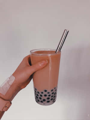 手拿著一杯有木薯珍珠和金屬吸管的泡泡茶。 — 珍珠奶茶 壁紙
