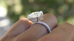 一隻手戴著一枚帶有大橢圓形主石的鑽石訂婚戒指的特寫。 — 結婚戒指 壁紙