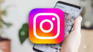 手拿著顯示Instagram應用程式標誌的電話。 — Instagram限時動態 壁紙