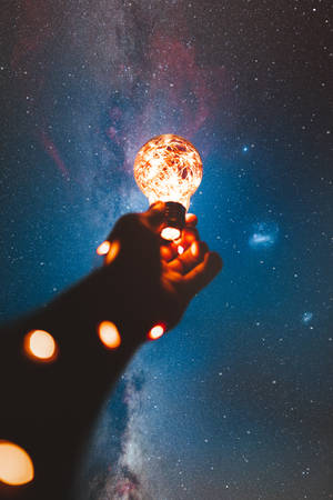 手在銀河下的星空夜空中拿著發光的燈泡 — 小米平板 壁紙