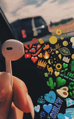 手在帶有有趣貼紙的手機附近拿著耳機 — 音樂美學 壁紙