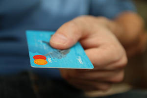 手拿著藍色Mastercard簽帳金融卡進行付款。 — 卡蒂 B 壁紙