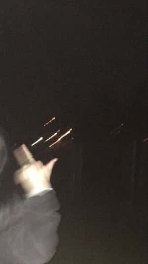 手握住發光物體，在黑暗的夜晚中創造光線條紋。 — 在這一刻 壁紙