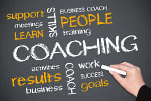 手在黑板上寫 coaching，附有商業和學習關鍵詞。 — 教練 壁紙