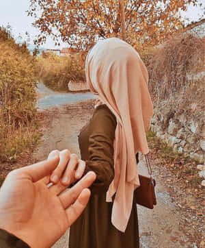 手牽著一位身穿米色頭巾的女子走在秋日小徑上。 — 情侶 壁紙