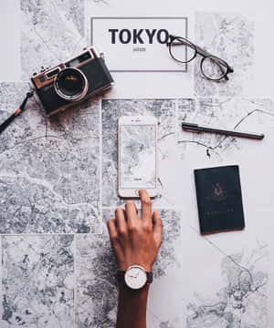 手在東京地圖上使用手機，搭配旅行物品規劃行程。 — Motorola Razr Ultra 2026 壁紙