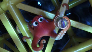 紅色卡通章魚拿著玻璃杯，裡面有紫色小生物，在黃色管道內。 — 章魚哥的觸手 壁紙