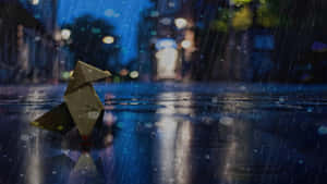 雨夜中，金色摺紙鳥站在濕漉漉的城市街道上，燈光模糊。 — 下雨 壁紙