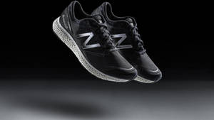 帶有銀色標誌的黑色 New Balance 運動鞋在攝影棚燈光下漂浮。 — New Balance 壁紙