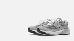 純白色背景上的灰色 New Balance 運動鞋，搭配白色鞋帶和厚鞋底。 — 中性 壁紙