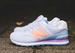 粉白色New Balance運動鞋，蜜桃標誌和紫色鞋底，置於石地。 — New Balance 壁紙