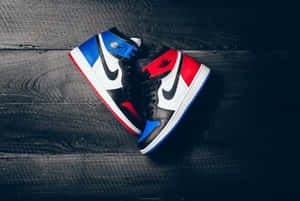 深色木地板上的紅、藍、黑色 Jordan 1 運動鞋。 — Jordan球鞋 壁紙