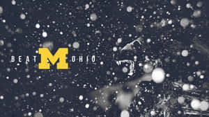 一頭獅子在飄落的雪花中咆哮，旁邊是黃色的「M」和「BEAT OHIO」文字。 — 密西根大學橄欖球 壁紙