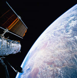 帶太陽能板的衛星環繞地球運行，顯示彎曲地平線和雲層 — 宇宙 壁紙
