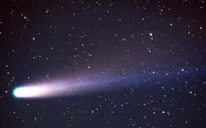 一顆帶有發光尾巴的彗星在夜空中的星星之間閃耀。 — 月夜星空 壁紙