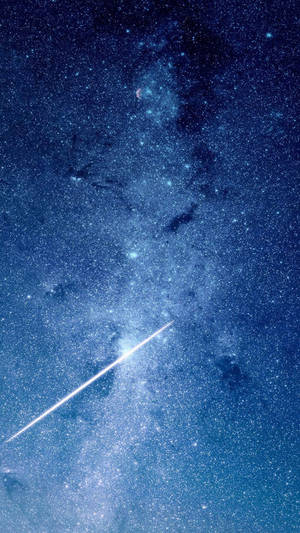 一顆明亮的流星在佈滿宇宙雲層的繁星藍色夜空中留下一道軌跡。 — iPhone Se 壁紙