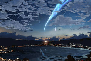 一顆發光的藍色彗星在黃昏時分劃過沿海小鎮上空，小鎮燈光閃爍，群山暗沉。 — 星星 壁紙