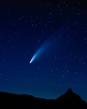 一顆發光的藍色彗星在山峰上方的繁星夜空拖曳著尾巴。 — 月夜星空 壁紙