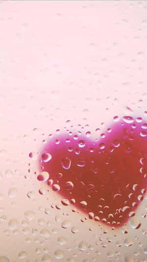 透過雨水浸濕的玻璃看到粉紅色心臟和水滴。 — 海灘日落 壁紙