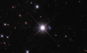 一顆明亮的星星在黑暗的星空中有光線，背景有星系。 — 星星 壁紙