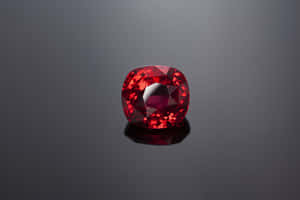 一顆拋光的紅色紅寶石在深灰色反光表面上。 — MacBook Air 15 壁紙