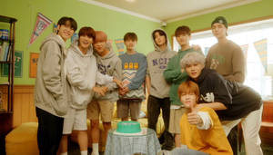 七位年輕男性在裝飾過的房間裡用蛋糕慶祝。 — Nct 127 壁紙