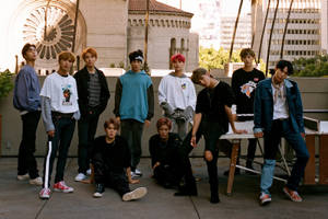 七位身穿休閒服裝的年輕男性在歷史建築附近的屋頂上擺姿勢。 — Nct 127 壁紙