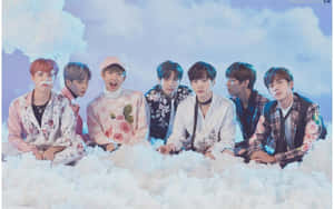 七位身穿花卉服裝的 K-pop 偶像面帶笑容坐在雲朵上。 — 日式審美桌面 壁紙