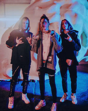 三位穿著前衛街頭服的年輕人做出搖滾手勢。 — ASAP Rocky 壁紙