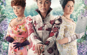 三位穿著華麗花卉連衣裙的女士站在花園裡，手持一本書。 — 柏捷頓家族 壁紙