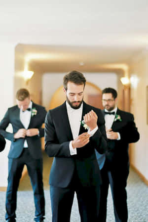 三位穿著禮服的男士在室內調整他們的蝴蝶結和襟花。 — 2:3 壁紙
