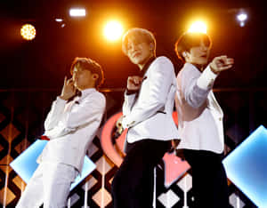 三位身穿白色西裝的男性表演者在燈光明亮的舞台上跳舞。 — BTS V 動圖 壁紙