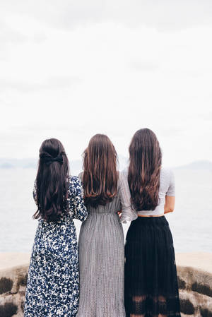 三位穿著連衣裙的女性一起站在懸崖上俯瞰大海。 — 少女前線 壁紙