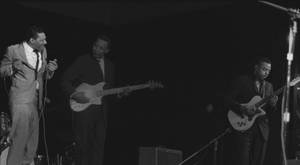 三位音樂家在舞台上以黑白現場表演 — 復古 壁紙