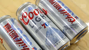 三個帶有費城76人標誌的Coors Light啤酒罐放在木頭上。 — 麥迪遜·比爾 壁紙